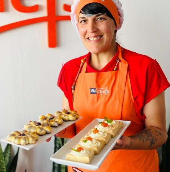La Bruja sonriendo con dos bandejas de pastelería