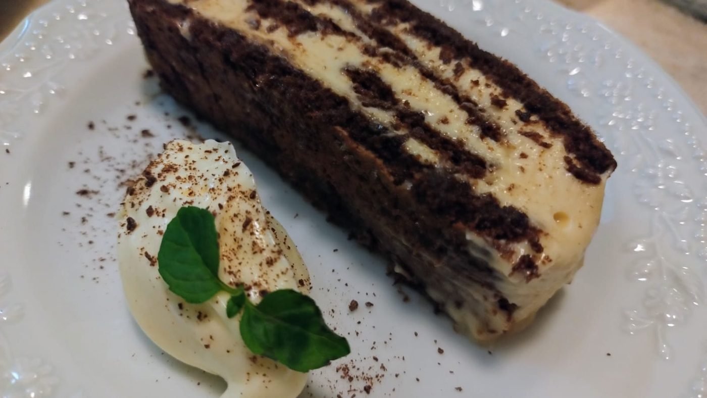 Porción de torta de chocolate con crema y hoja de menta