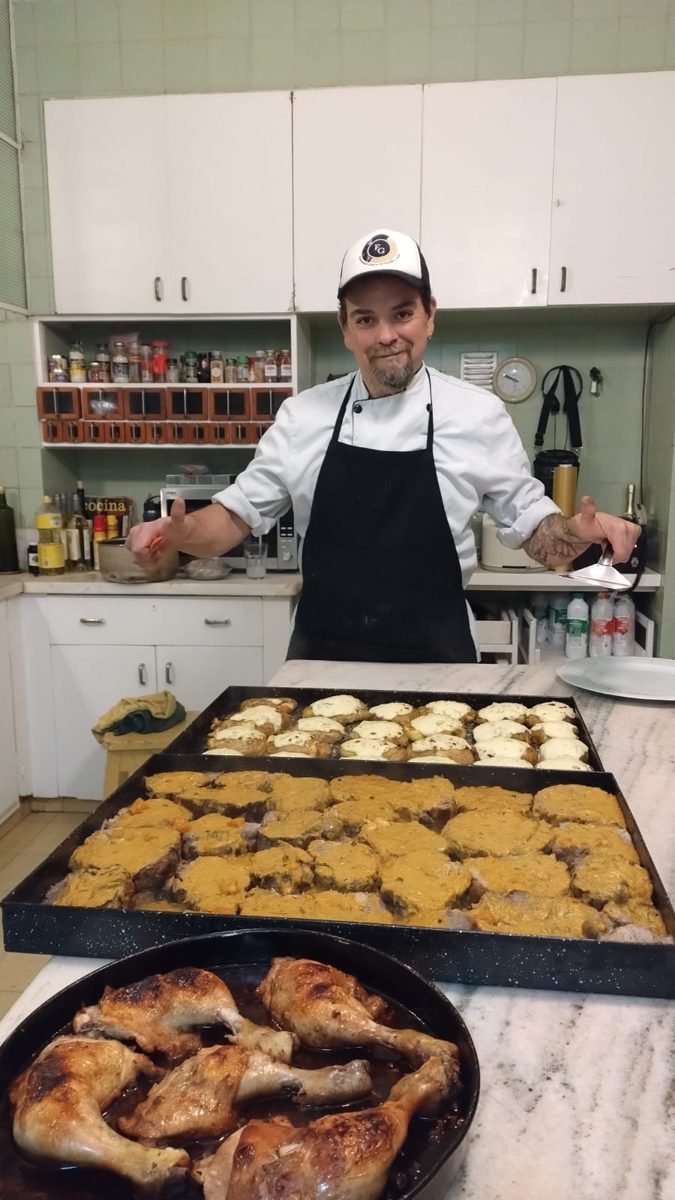 El Mago junto a bandejas de carnes, papas gratinadas y pollo al horno para un evento